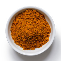 Ground masala spice mix in white ceramic bowl isolated on white from above.