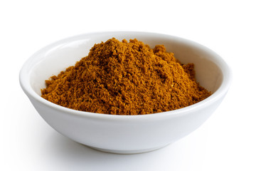 Ground masala spice mix in white ceramic bowl isolated on white.