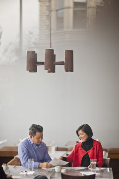 Two mature colleagues discuss a business deal over coffee in a local cafe.