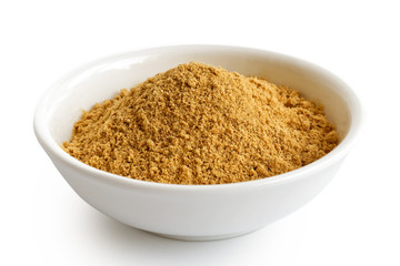 Finely ground dry ginger in white ceramic bowl isolated on white.