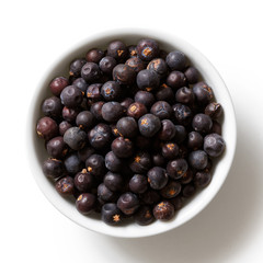 Dried juniper berries in white ceramic bowl isolated on white from above.