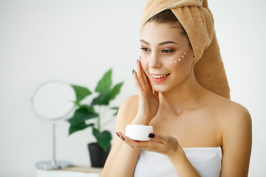 Skin care. Woman with healthy face applying cosmetic cream under the eyes