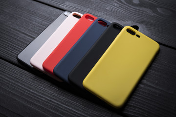 Mobile multicolored phone covers or phone cases on black wooden background