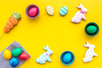 Sweets for celebrate Easter. Gingerbread in shape of easter bunny and easter eggs. Yellow background top view copy space
