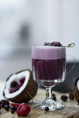  lilac cocktail with berries and coconut on a wooden table