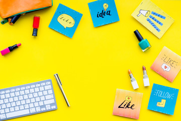 Female blogger concept. Work desk with keyboard, cosmetics and social media icons on yellow desk top view space for text