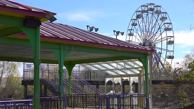 An abandoned and graffiti covered ferris wheel at an amusement park presents a spooky and haunted image.