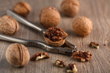 Walnut kernels and whole walnuts on rustic old wooden table.