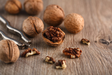 Walnut kernels and whole walnuts on rustic old wooden table.