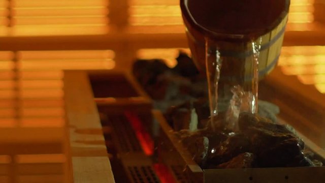 Pouring cold water on hots stones in the sauna