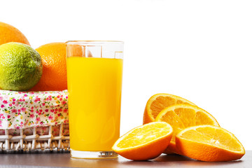 Glass with orange juice and sliced orange slices isolated on white background. Fresh orange fresh. Oranges in a basket next to fresh squeezed juice in a glass beaker.