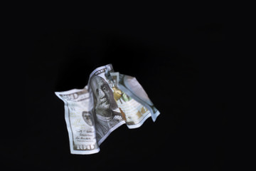 a crumpled dollar on the black background