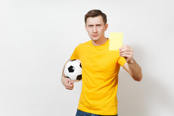 Young serious severe European man, football referee or player in yellow uniform showing yellow...