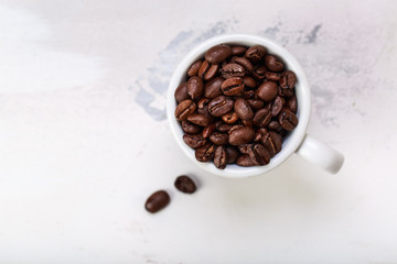Coffee beans in white coffee cup brown white background