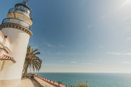 A lighthouse in front of the calm waters of the mediterranean sea. It's a sunny day in the coast of Calella in Catalonia, Spain.