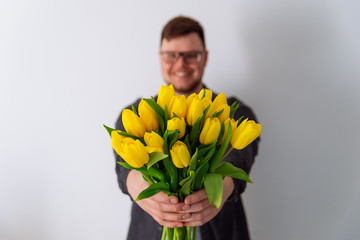 man holds bouquet of yellow tulips in front of him. romantic gift for woman. white background