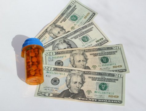 Pill containter with twenty dollar bills beside it