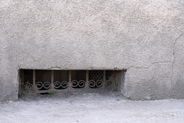 Small dark basement window with rusted steel lattice