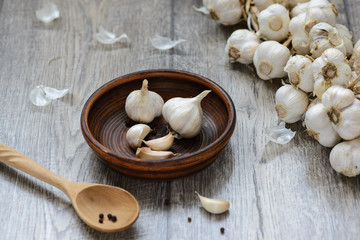 garlic in a clay plate with a wooden spoon on the table