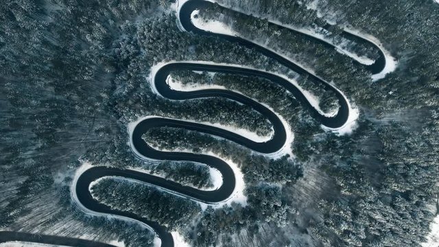 Aerial reveal shot of a frozen mountain road in winter