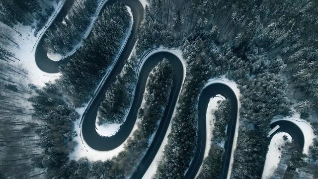 Aerial reveal shot of a frozen mountain road in winter