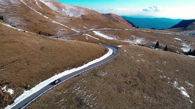 Aerial tracking shot of a car on a mountain road