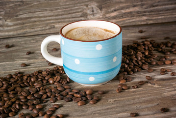 Photo of a close-up of a cup of fragrant coffee on a background of coffee beans and a wooden table