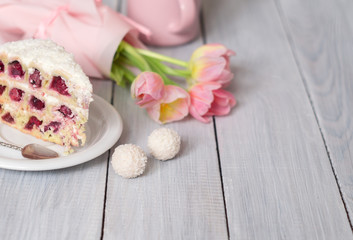 Fototapeta na wymiar A cake with cherries and pink tulips on white wooden table