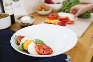 A caprese salad being assembled in a kitchen 