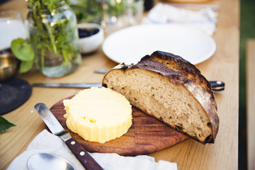 Half a loaf of rustic bread and a round of butter on a cutting board