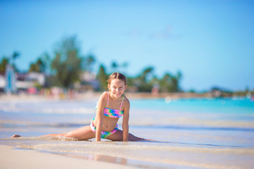 Adorable little girl in shallow water on white beach