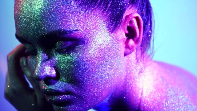 Fashion model woman in colorful bright sparkles and neon lights posing in studio, portrait of beautiful sexy girl. Art design colorful vivid makeup. Slow motion 4K UHD video footage. 3840X2160