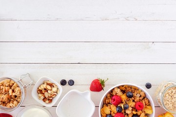 Cereal and ingredients for a healthy breakfast forming a bottom border over a white wood...