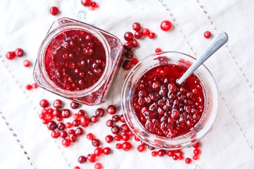 Jam bank with red berries top view on a white tablecloth