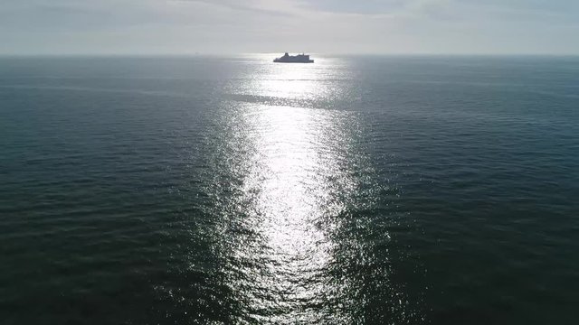 Aerial bird view footage of large ship moving over ocean in sun reflection quiet sea beautiful weather ships have been important contributors to human migration and commerce 4k high resolution