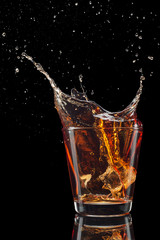 Glass of whiskey with splash isolated on black background