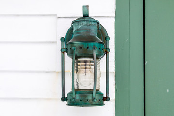 A vintage style green lantern attached to a lighthouse. 