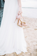 Fototapeta na wymiar High heel shoes in young woman hands on beach.