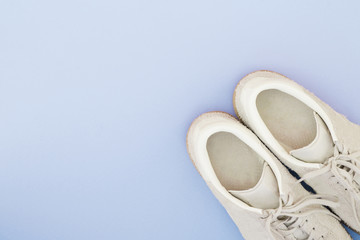 White sneakers on a pastel blue background. Minimalistic Flat lay composition with place for text. Shoes on a bright blue background