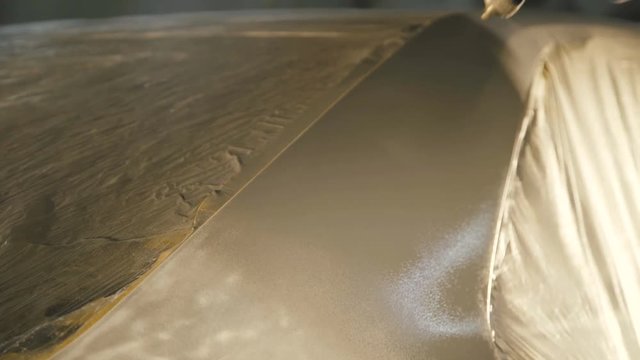Mechanic spraying primer on a car surface. 4K