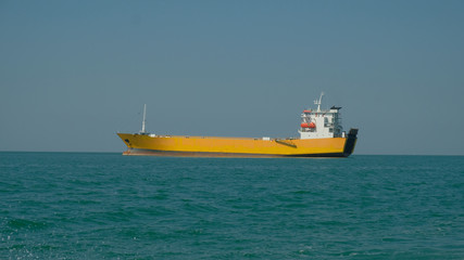 yellow cargo ship at sea on a summer day