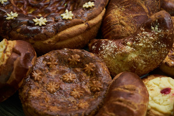 Traditional Russian Easter baked goods, kulichi, patties with cottage cheese, karavai and loaf cake with nuts on festive table background