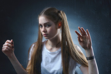 A beautiful, young girl is sad for a blind window
