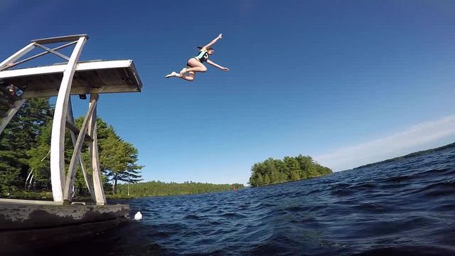 young girl jumps from floating tower into water slow motion