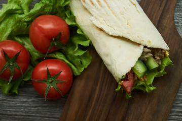 Shaurma sandwich chicken roll in a pita with fresh vegetables tomatoes , cucumber, latitude, cheese...