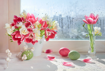 Pink tulips and white freesia flowers with Easter decorations on the window board