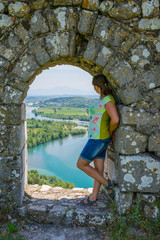 Fototapeta na wymiar A young girl looks dreamily at the window of the fortress of Rozafa in Albania.