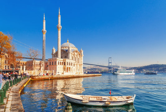 Ortakoy cami - famous and popular landmark in Istanbul, Turkey. Lovely spring scenery with fishing boat at foreground and old historical mosque Ortakoy and Istanbul Bosporus bridge at background.