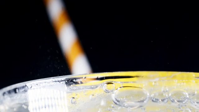 Slow motion shot of slice of lemon in soda water.