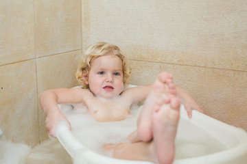 smiling child bathing in the bathroom with foam
